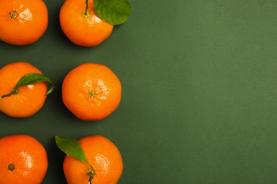 Photo of Delicious tangerines and leaves on green background, flat lay. Space for text