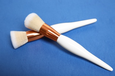 Photo of Two professional makeup brushes on blue background