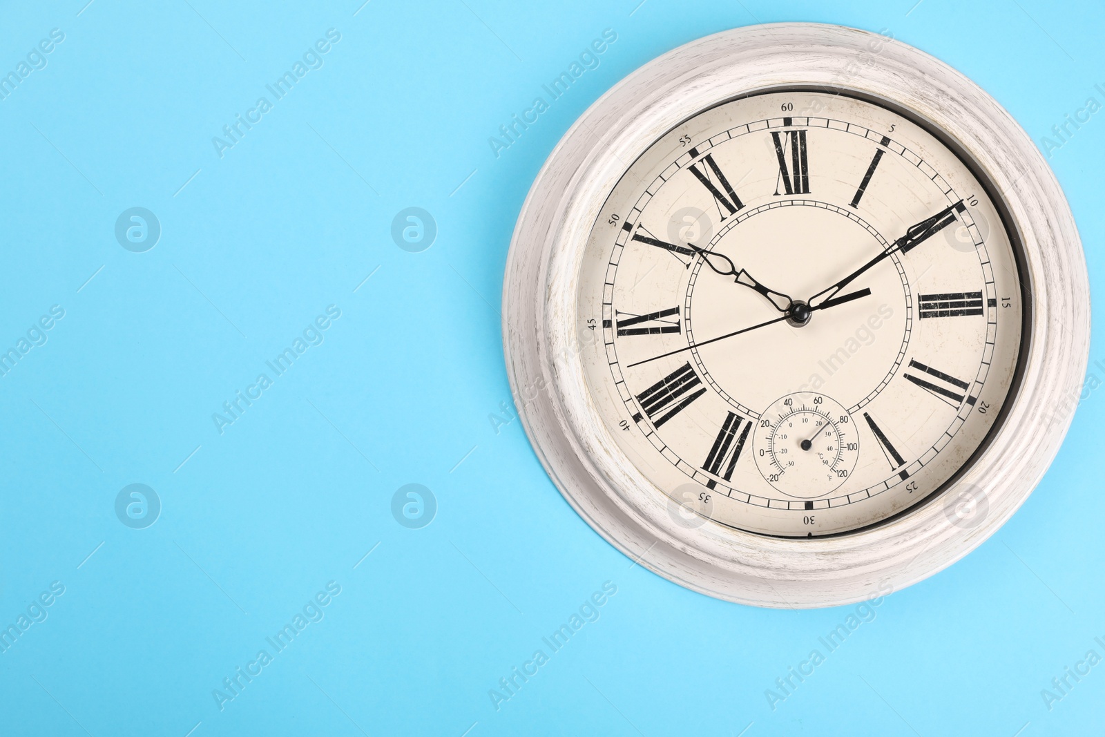 Photo of Stylish vintage wall clock on turquoise background, top view. Space for text