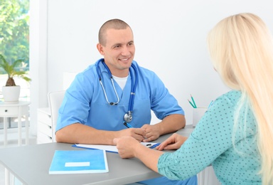 Male medical assistant consulting female patient in clinic