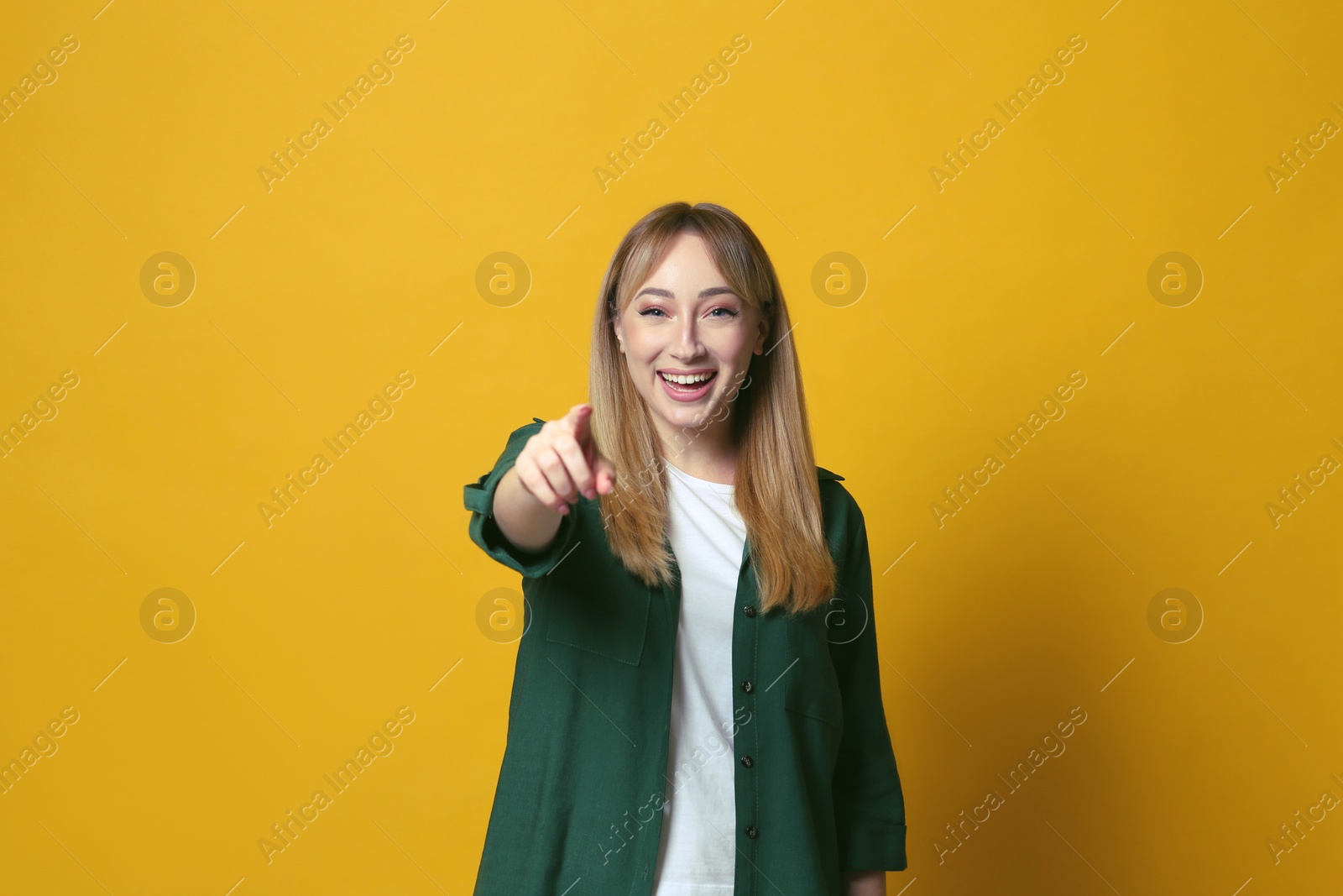 Photo of Beautiful young woman laughing on yellow background. Funny joke