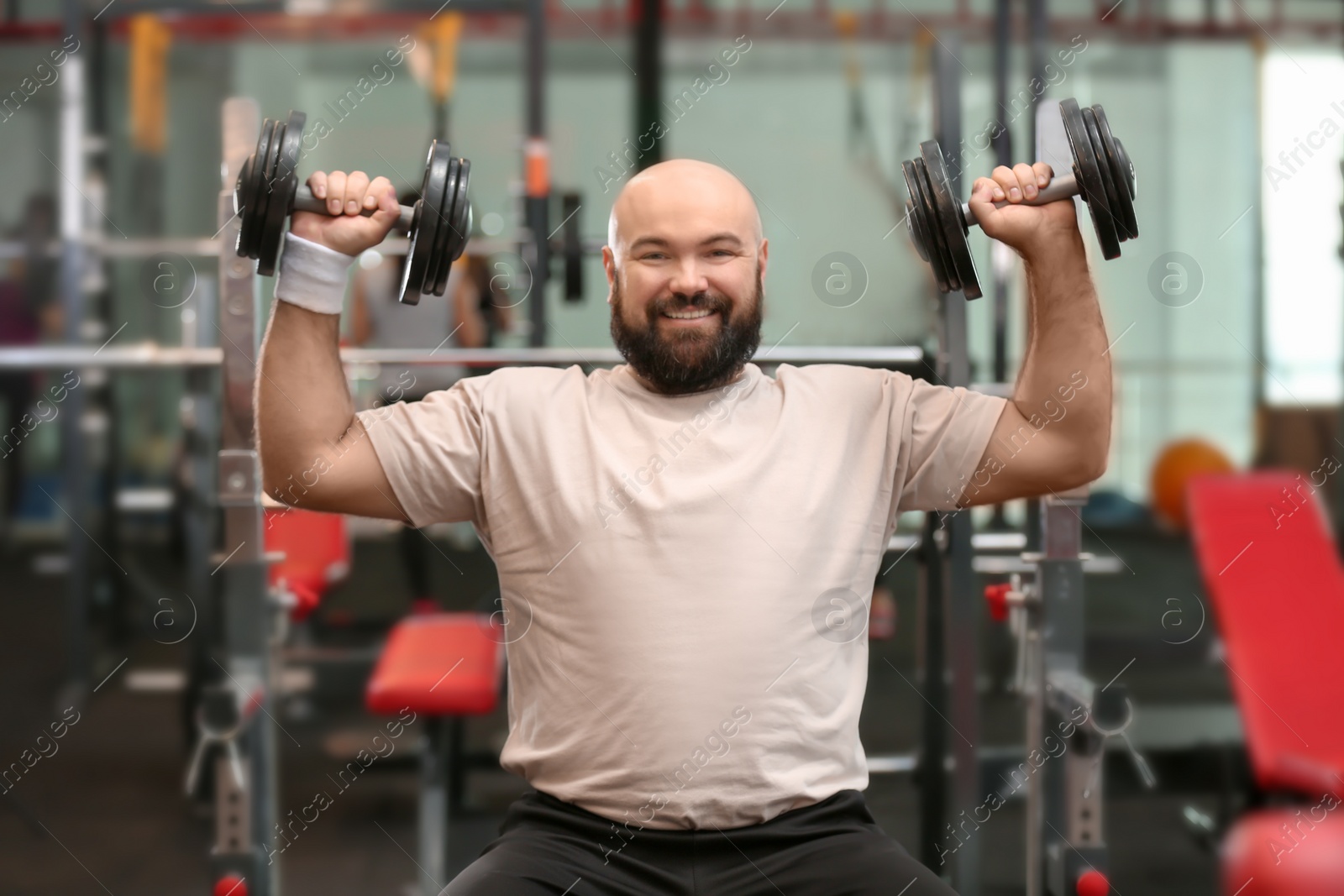 Photo of Overweight man training with dumbbells in gym