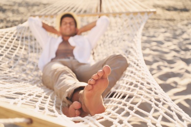 Man relaxing in hammock outdoors, focus on legs