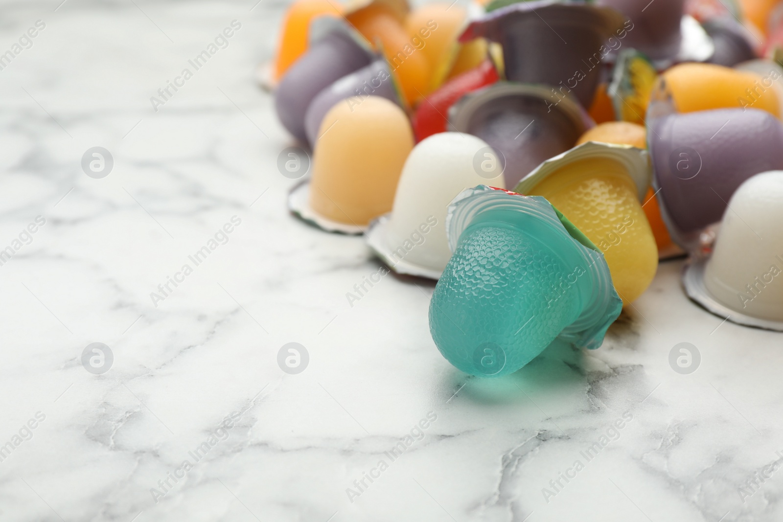 Photo of Tasty bright jelly cups on white marble table, space for text