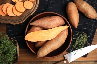 Photo of Sweet potatoes and thyme on wooden table, flat lay