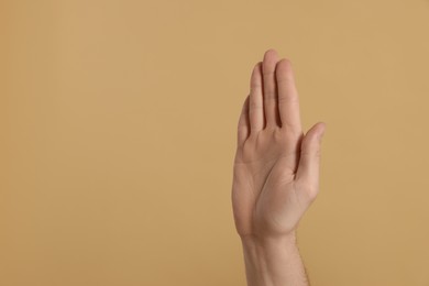 Photo of Man giving high five on beige background, closeup of hand. Space for text
