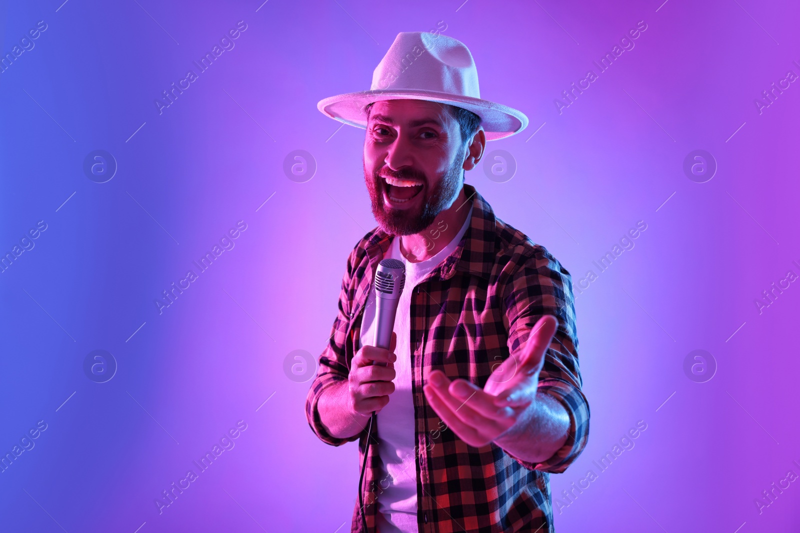 Photo of Emotional man with microphone singing in neon lights