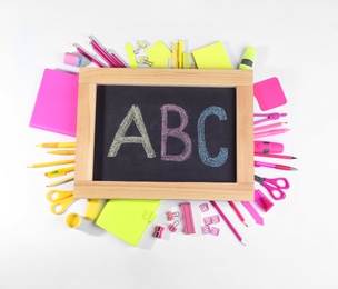Photo of Chalkboard with letters ABC and different stationery on white background, top view