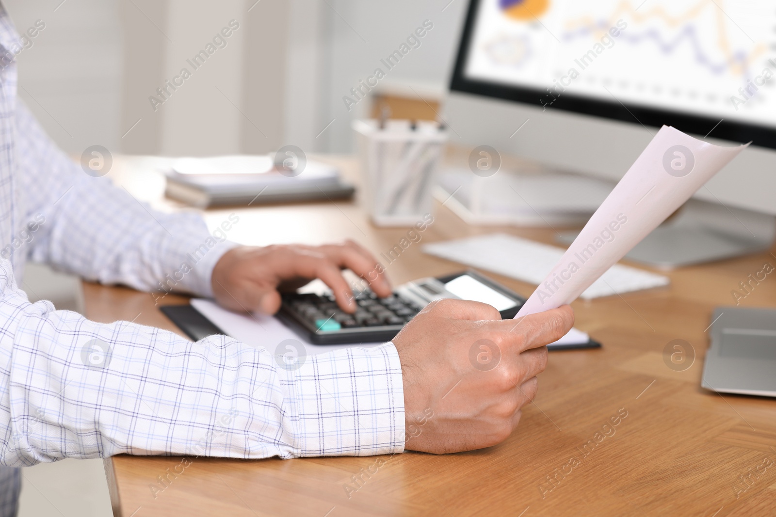 Photo of Professional accountant using calculator at wooden desk in office, closeup