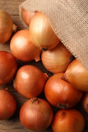 Photo of Many ripe onions on wooden table, flat lay