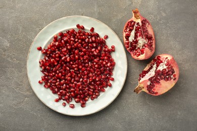 Photo of Tasty ripe pomegranate and grains on grey table, flat lay