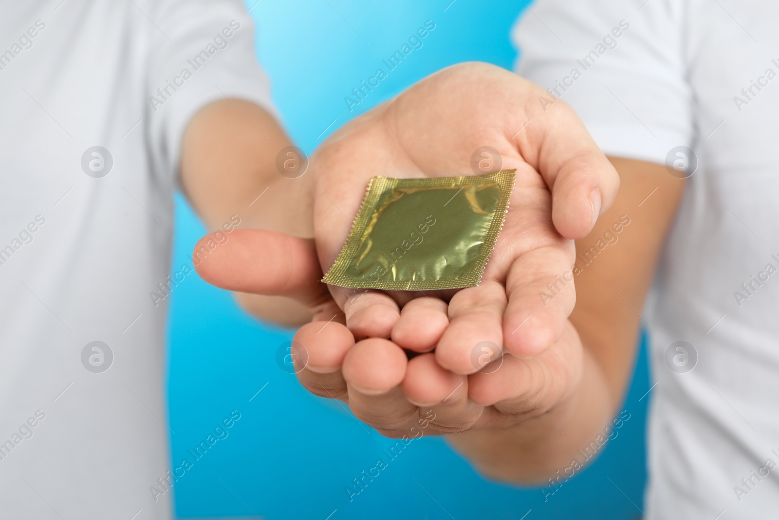 Photo of Gay couple with condom on light blue background, closeup