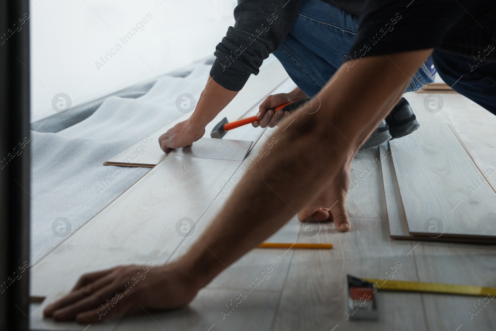 Photo of Workers installing new laminated flooring in room, closeup