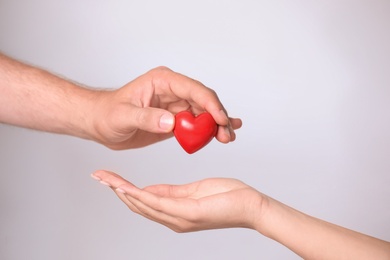 Photo of Man giving red heart to woman on white background, closeup. Donation concept