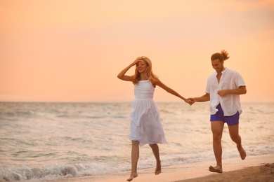 Photo of Young couple having fun on beach at sunset