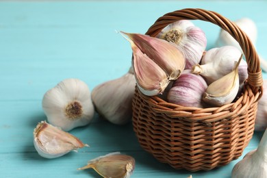 Photo of Fresh unpeeled garlic bulbs and cloves on light blue wooden table, closeup with space for text. Organic product