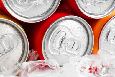 Energy drinks in wet cans and ice cubes, closeup