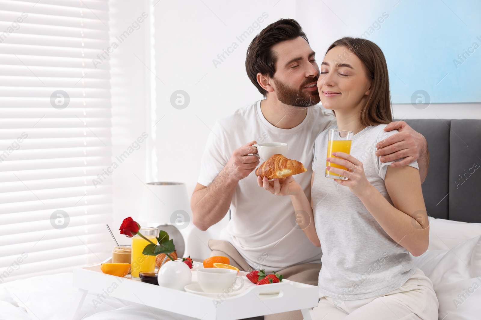 Photo of Lovely couple having breakfast in bedroom. Space for text