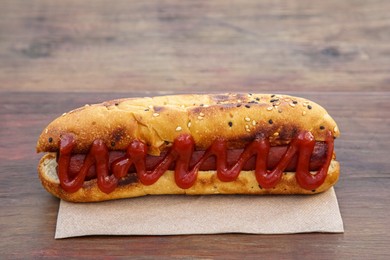 Photo of Fresh tasty hot dog with ketchup on wooden table, closeup