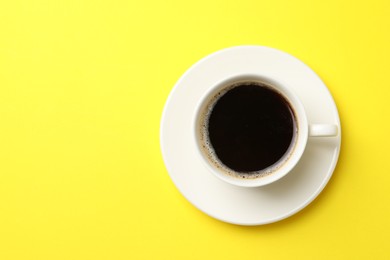 Photo of Cup of aromatic coffee on yellow background, top view. Space for text