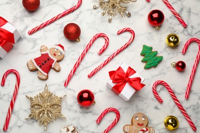 Flat lay composition with tasty candy canes and Christmas decor on white marble table