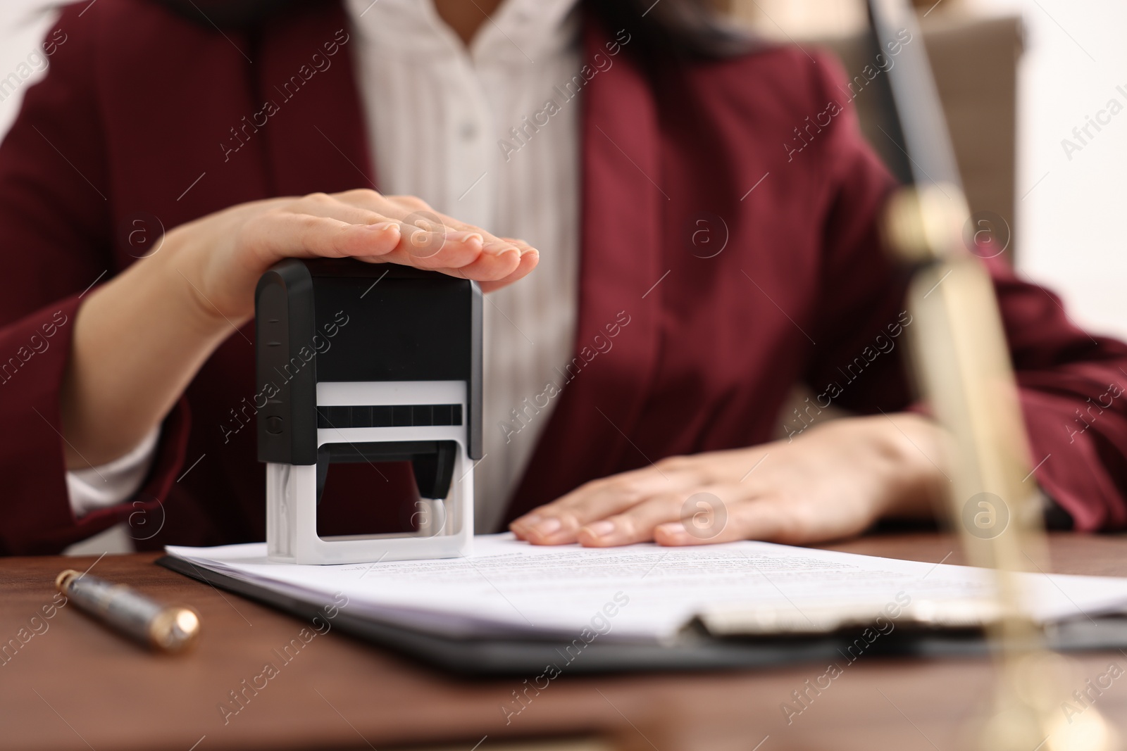 Photo of Notary stamping document at table in office, closeup