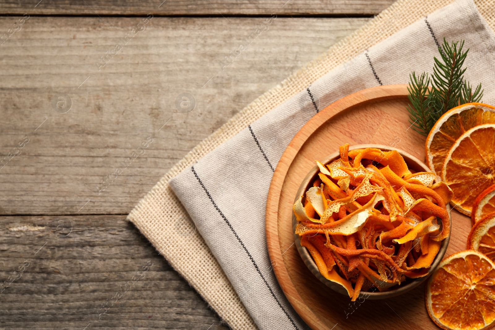 Photo of Dry orange peels and slices on wooden table, top view. Space for text