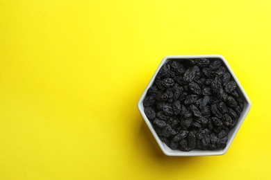 Bowl with raisins and space for text on color background, top view. Dried fruit as healthy snack