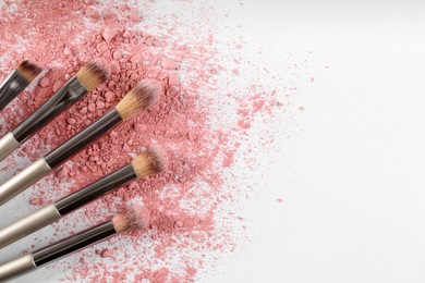 Makeup brushes and scattered eye shadow on white background, flat lay. Space for text