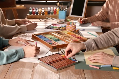 Photo of Artists drawing with soft pastels and pencils at table, closeup