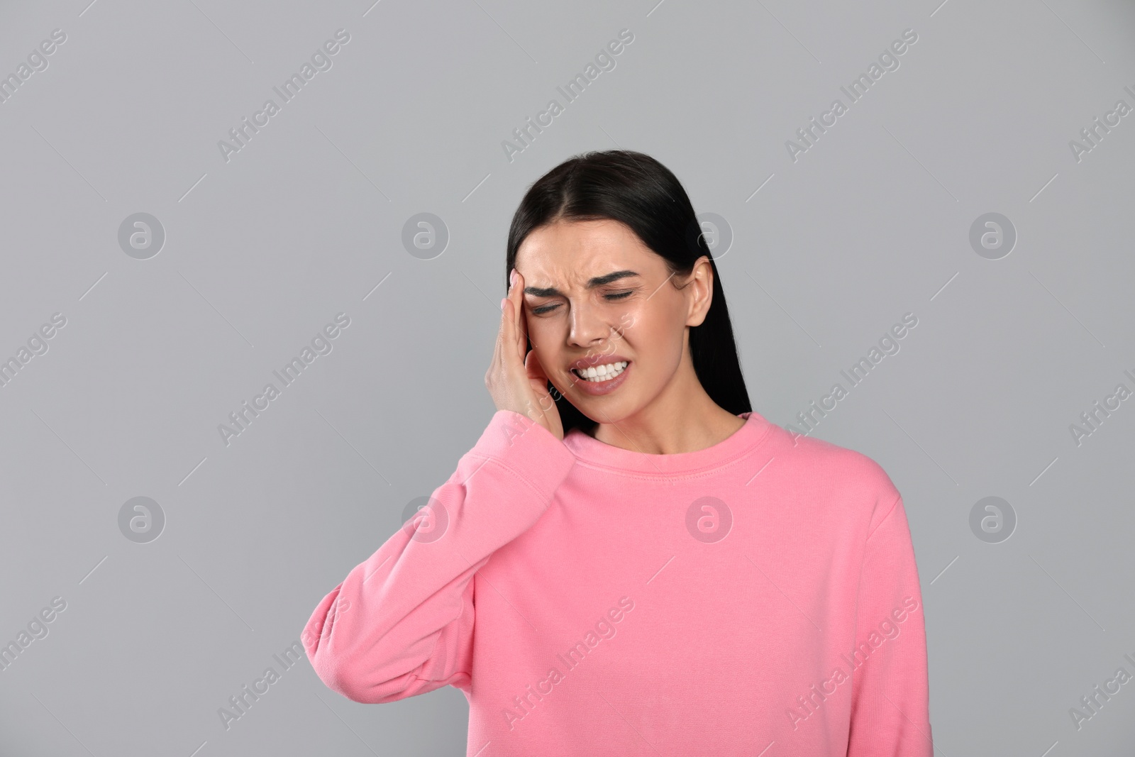 Photo of Woman suffering from migraine on grey background