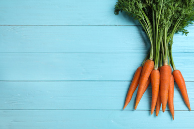 Ripe carrots on light blue wooden table, flat lay. Space for text
