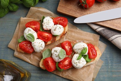 Delicious sandwiches with mozzarella, fresh tomatoes and basil on blue wooden table, flat lay