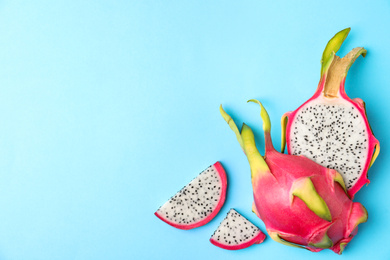 Photo of Delicious cut dragon fruit (pitahaya) on light blue background, flat lay. Space for text
