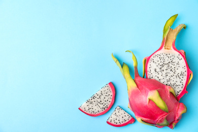 Delicious cut dragon fruit (pitahaya) on light blue background, flat lay. Space for text