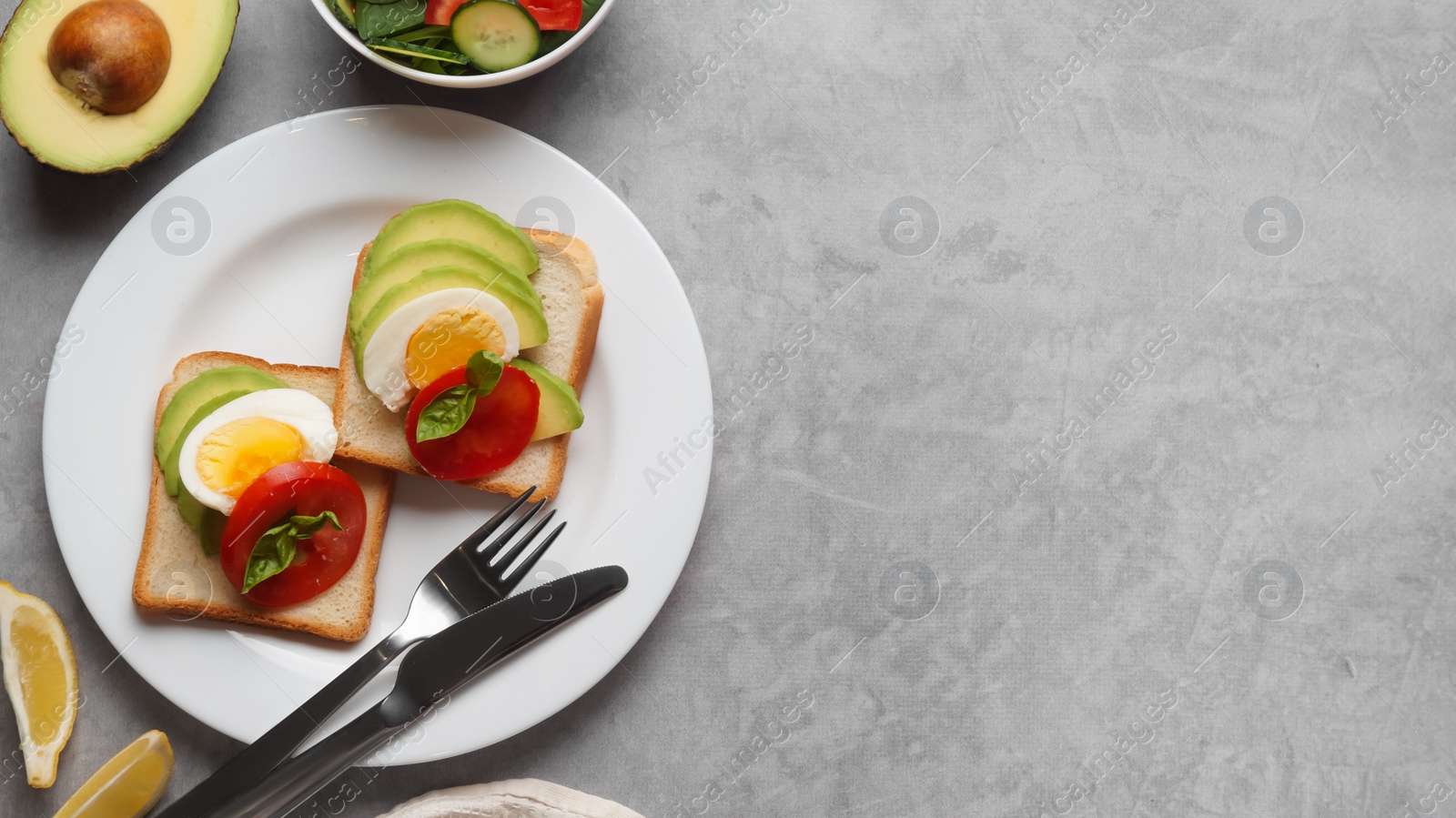 Photo of Tasty sandwiches with boiled egg, avocado and tomato served on grey table, flat lay. Space for text