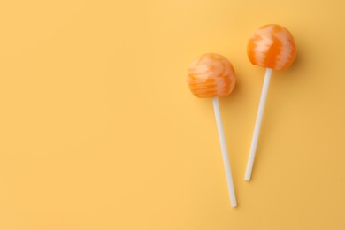 Photo of Tasty lollipops on orange background, flat lay. Space for text