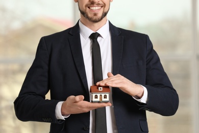 Real estate agent holding house model, indoors