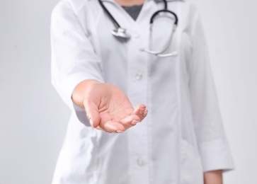Photo of Young female doctor offering helping hand on white background