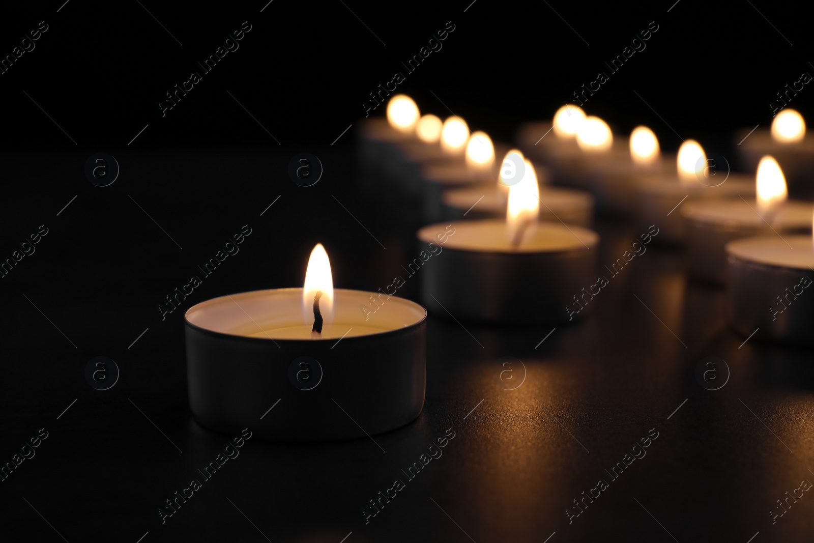 Photo of Burning candle on table in darkness, closeup with space for text. Funeral symbol