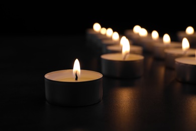 Photo of Burning candle on table in darkness, closeup with space for text. Funeral symbol
