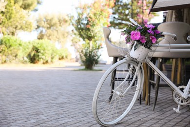 Retro bicycle with flowers in basket on outdoor terrace