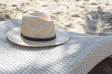Photo of Sunbed with stylish straw hat on sandy beach, space for text