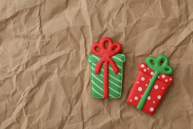 Photo of Christmas gift shaped gingerbread cookies on crumpled parchment, top view. Space for text