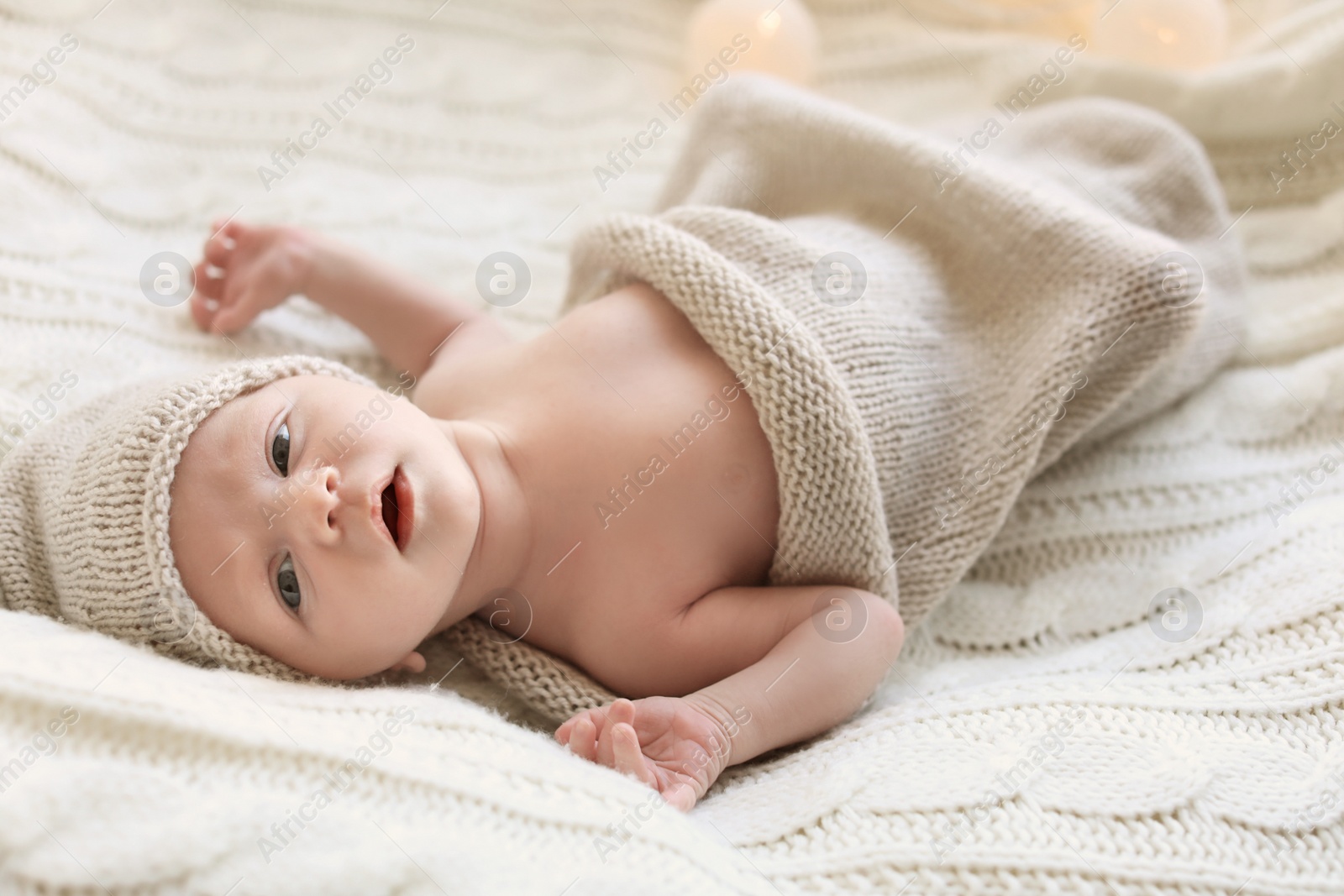 Photo of Adorable newborn baby in hat lying on bed