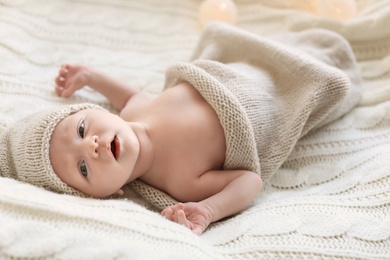 Photo of Adorable newborn baby in hat lying on bed