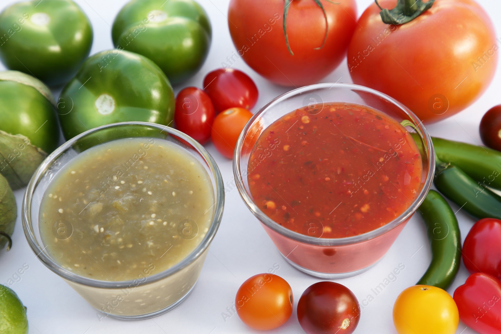 Photo of Bowls with delicious salsa sauces and ingredients on white background, closeup