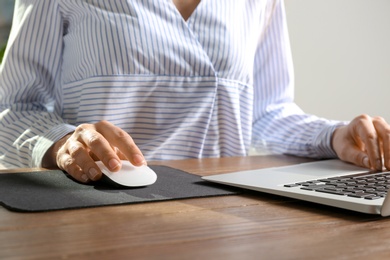 Photo of Woman using computer mouse with laptop at table, closeup