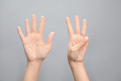 Photo of Woman showing sign eight on grey background, closeup. Body language
