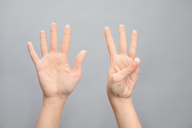 Woman showing sign eight on grey background, closeup. Body language